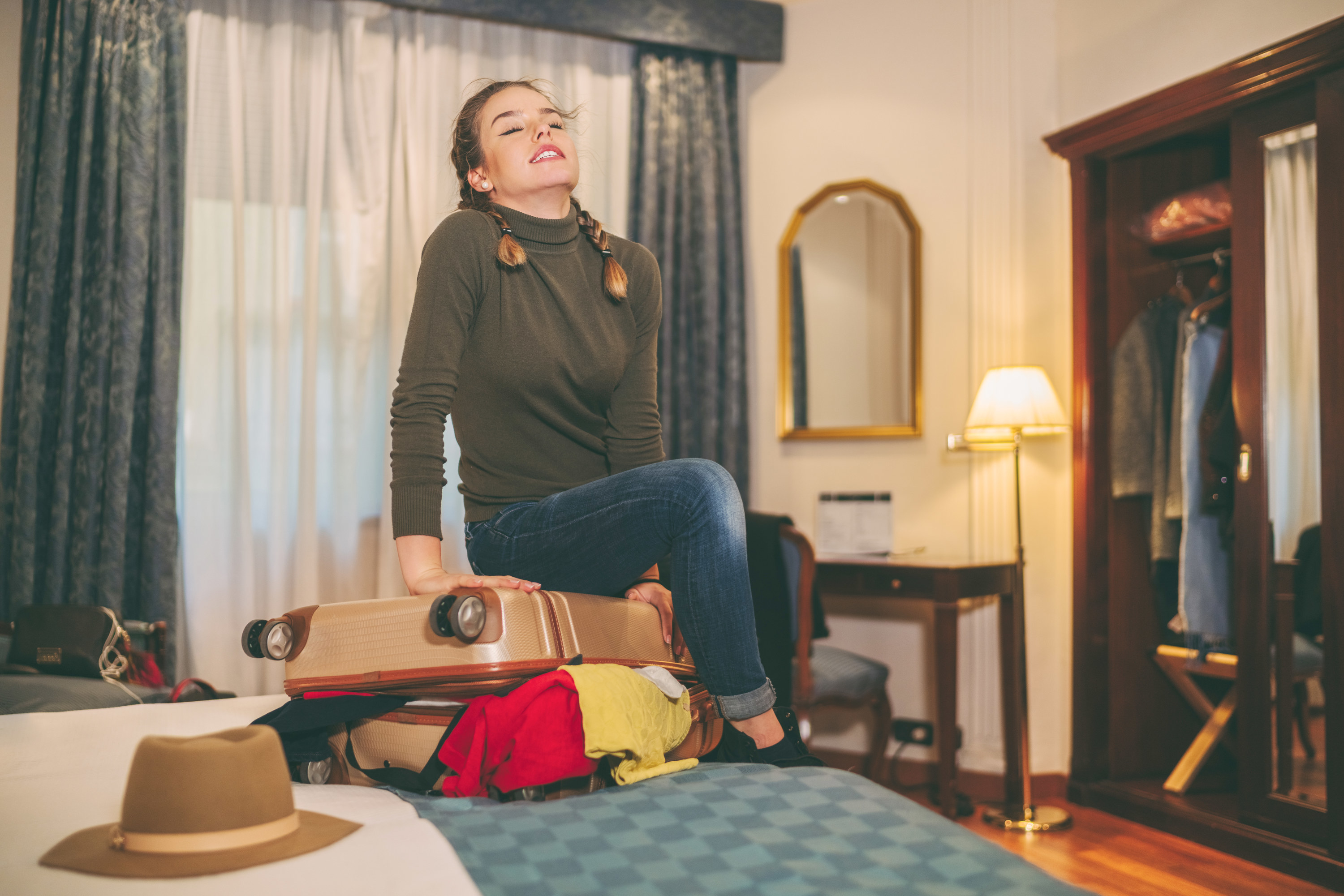 a person sitting on a suitcase in a hotel