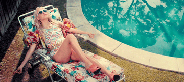 A woman laying by the pool and shaking her shoulders
