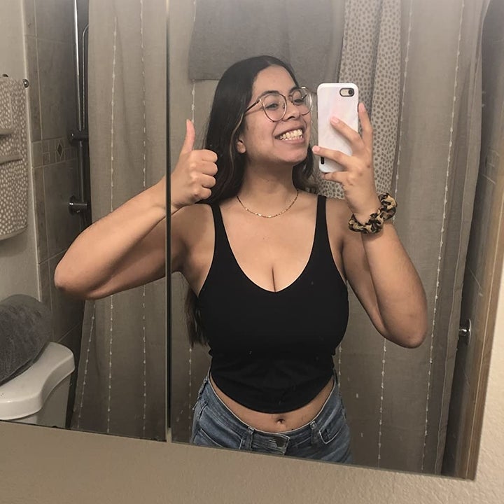 reviewer with a 32H chest wearing the black version and smiling while taking a mirror selfie