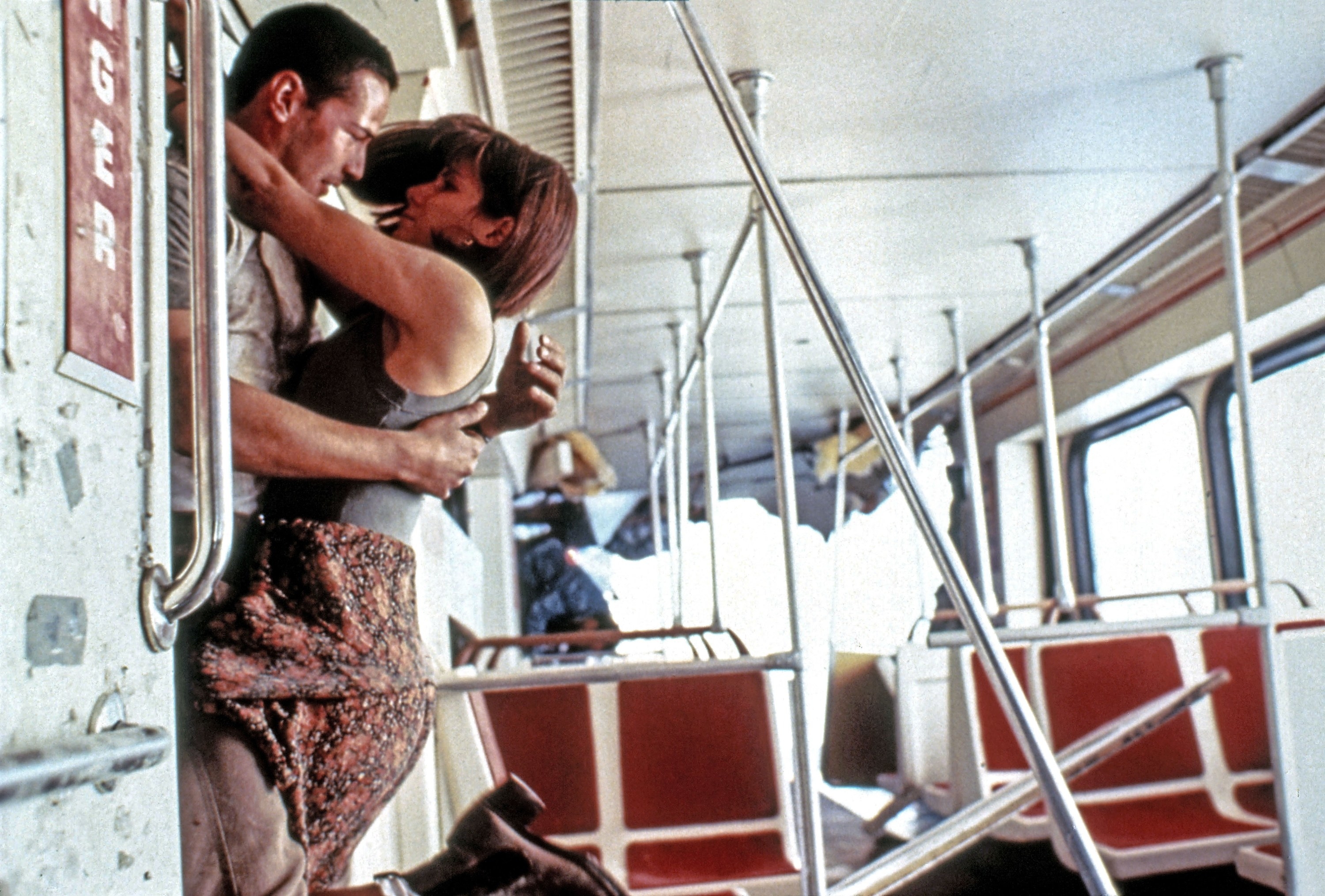 A woman jumps up into the arms of a man on a bus