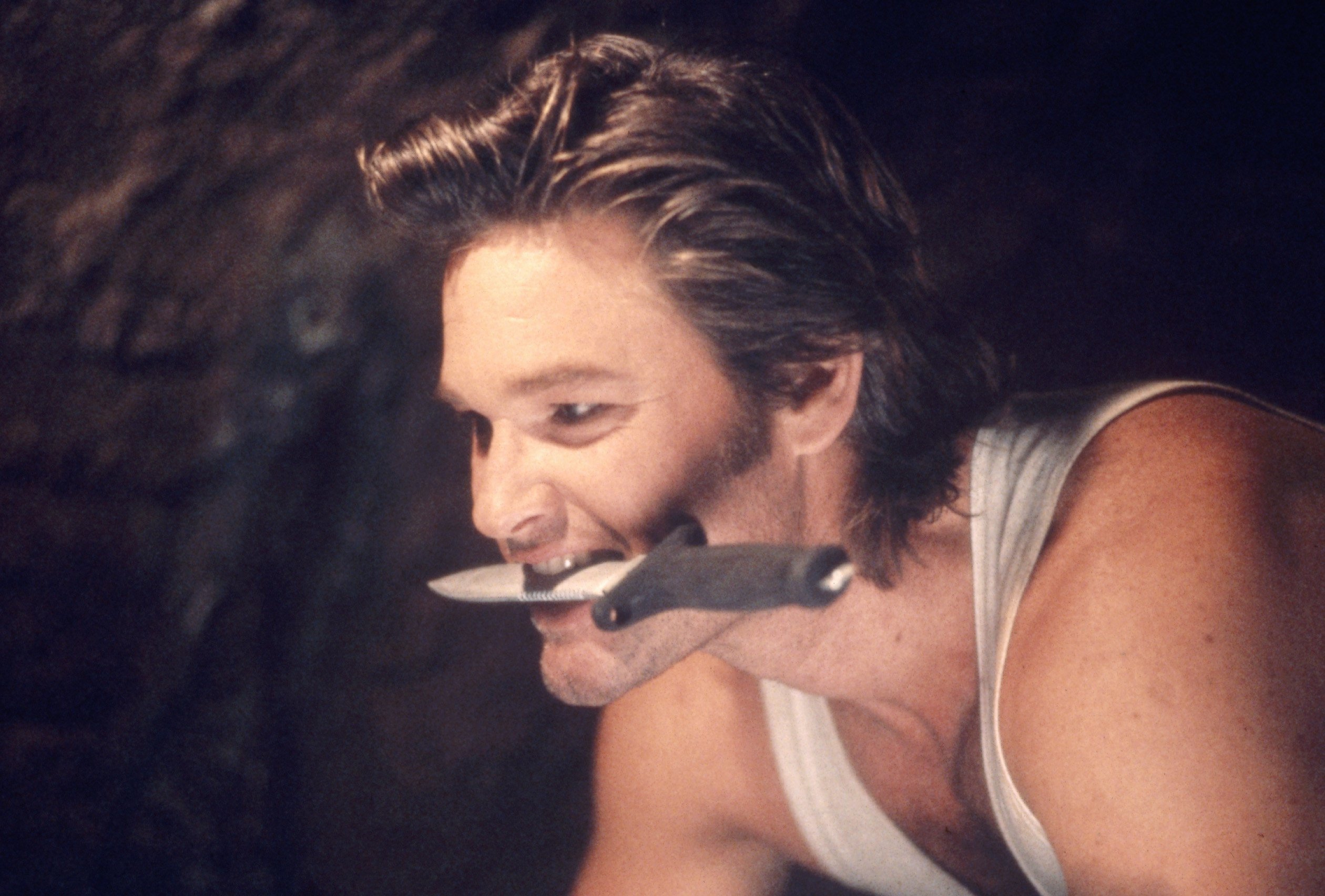 Kurt Russell with a knife in his mouth.
