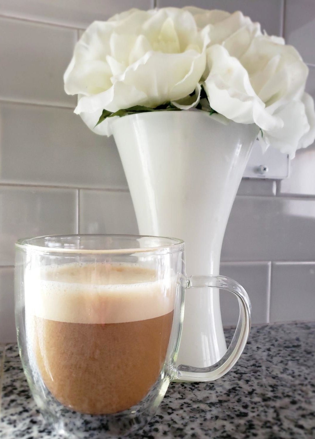 Reviewer image of clear coffee mug with beverage inside in front of white vase
