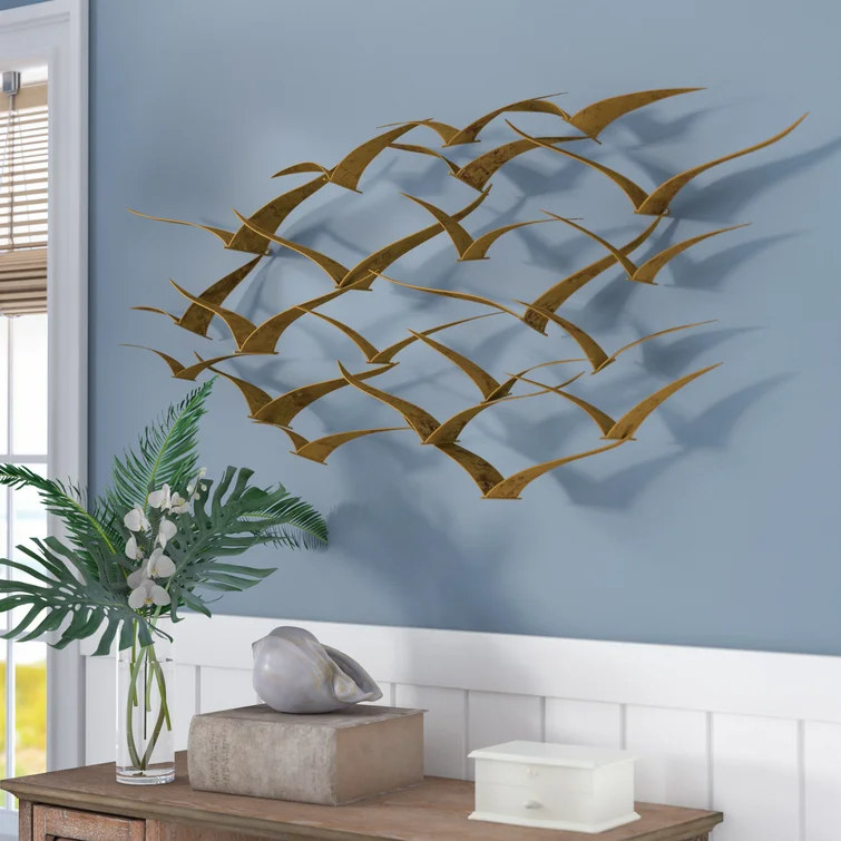 Gold faux birds mounted on blue wall above wooden console table