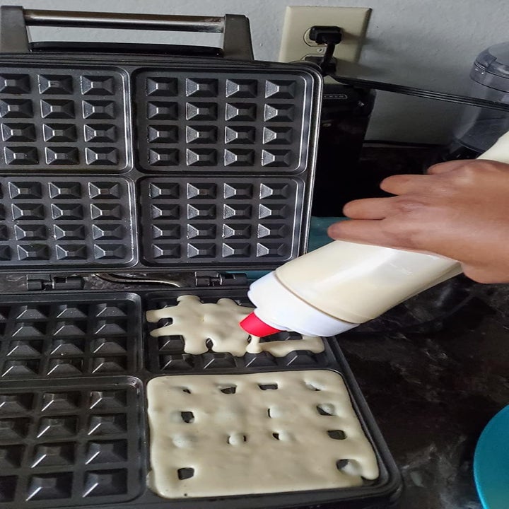 hand squirting batter into a waffle maker