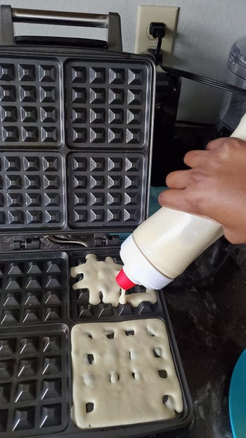 reviewer photo of a hand squirting batter into a waffle maker