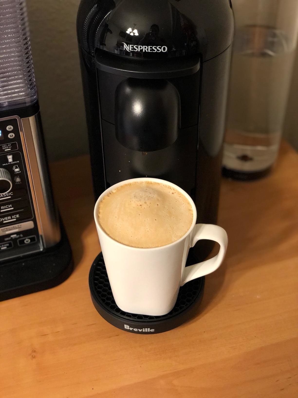 A reviewer&#x27;s black nespresso making frothy coffee