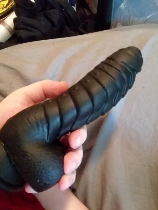 Reviewer holding black textured dildo