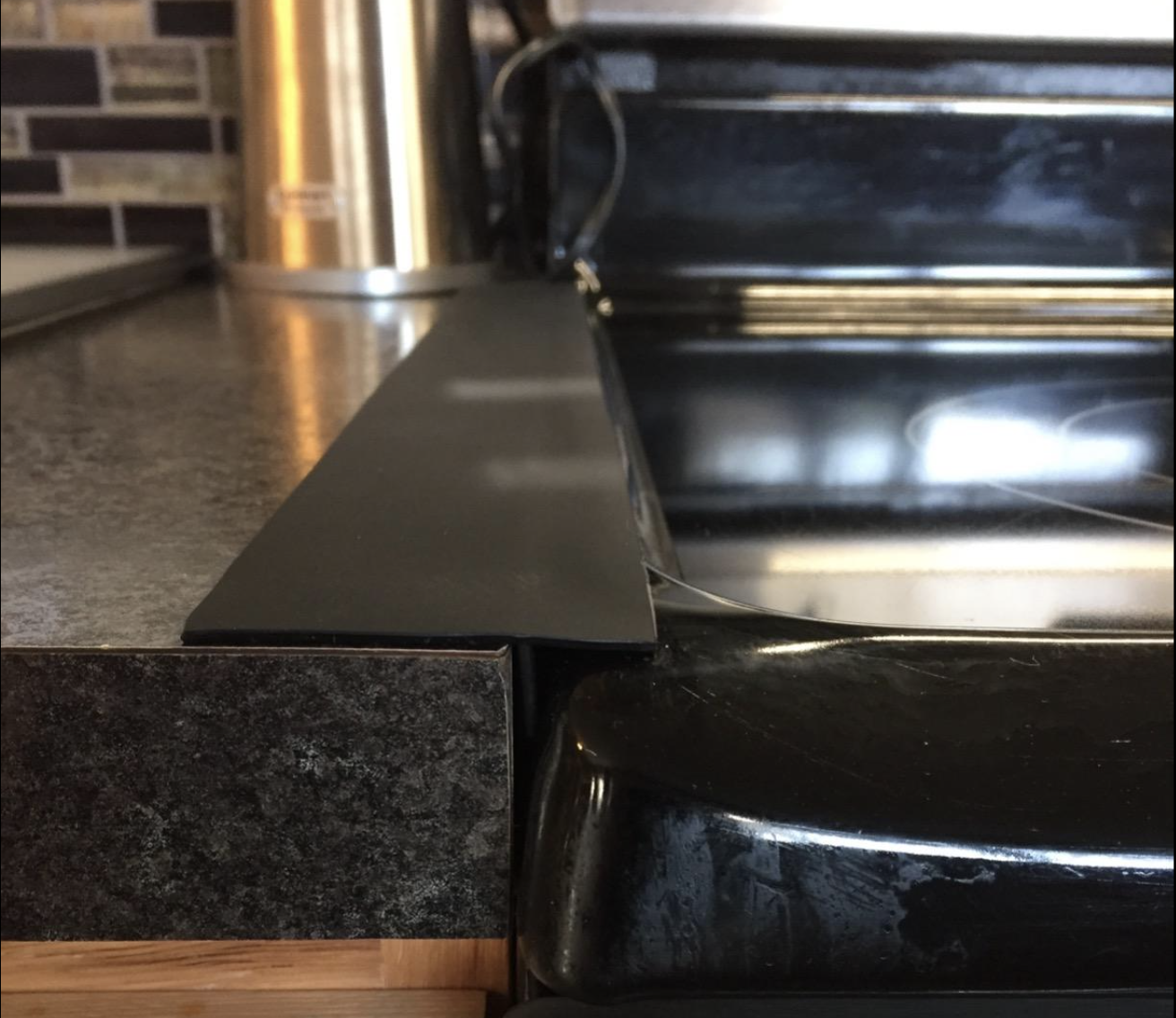 Reviewer&#x27;s picture of the gap cover placed between their stove and counter