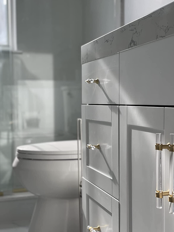 a reviewer's bathroom cabinets with the acrylic and gold pulls