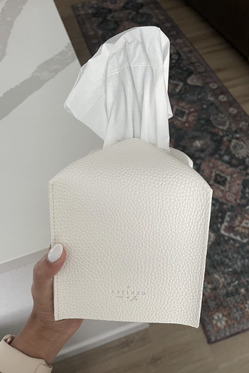 a reviewer holding a white faux leather tissue box cover