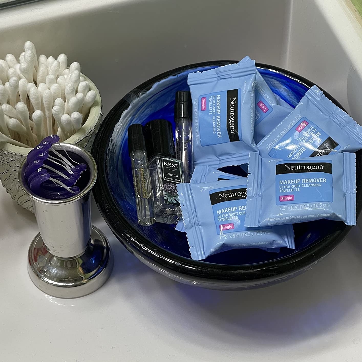 Reviewer image of individual make up remover packets in a bowl next to containers with floss picks and q-tips