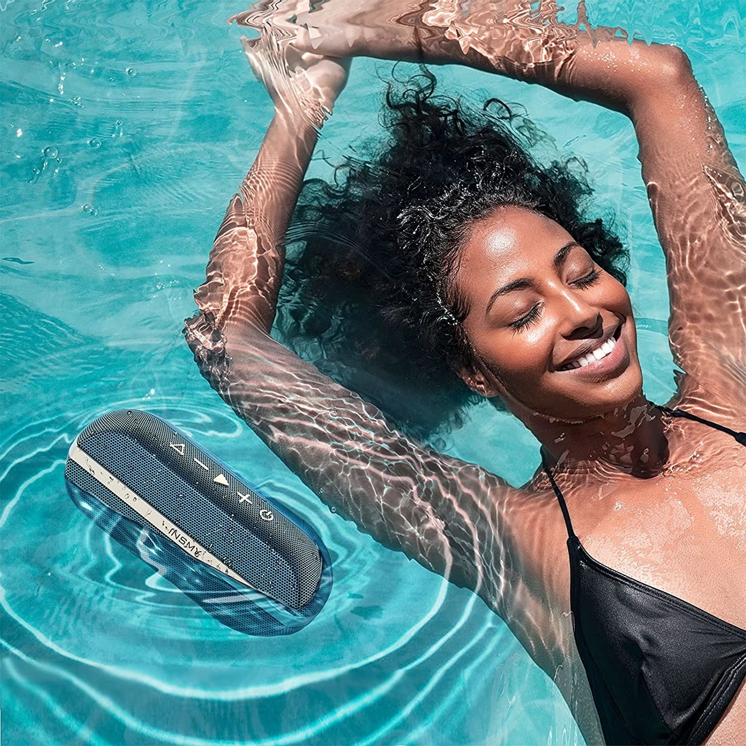 a model floating in a pool with a blue speaker floating next to them