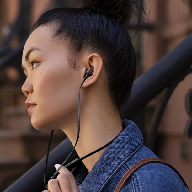 A model wearing a pair of black wireless Beats headphones