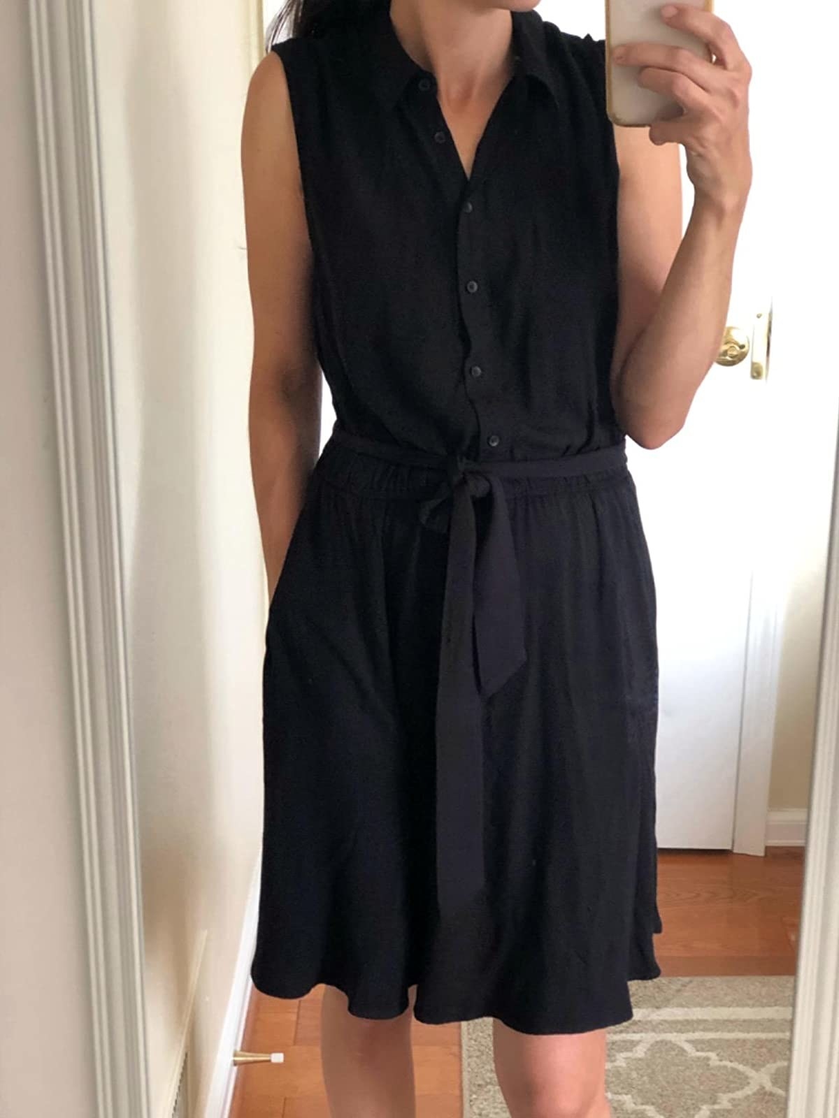 reviewer wearing the black tie-waist dress with button-front top half and collar neckline