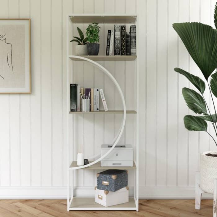 The white, semicircle bookshelf with books on it