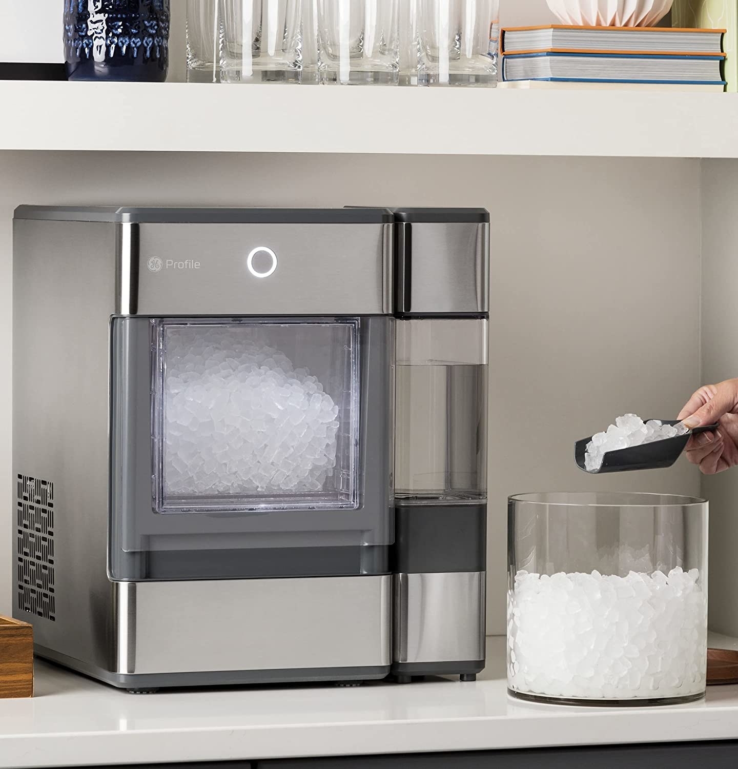 Gray square shaped ice maker perched on a kitchen counter with nugget ice inside