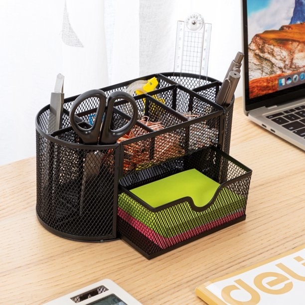 A black desk organizer with office supplies inside