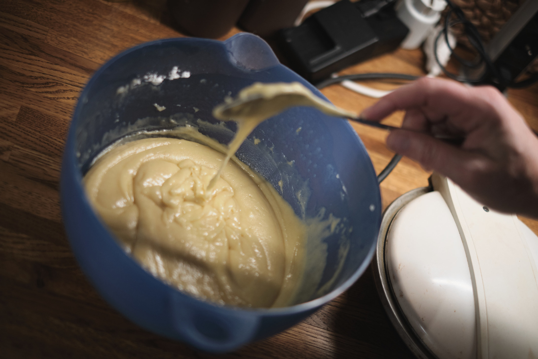 Hand with spoon mixing cake batter for Christmas baking in a blue bowl
