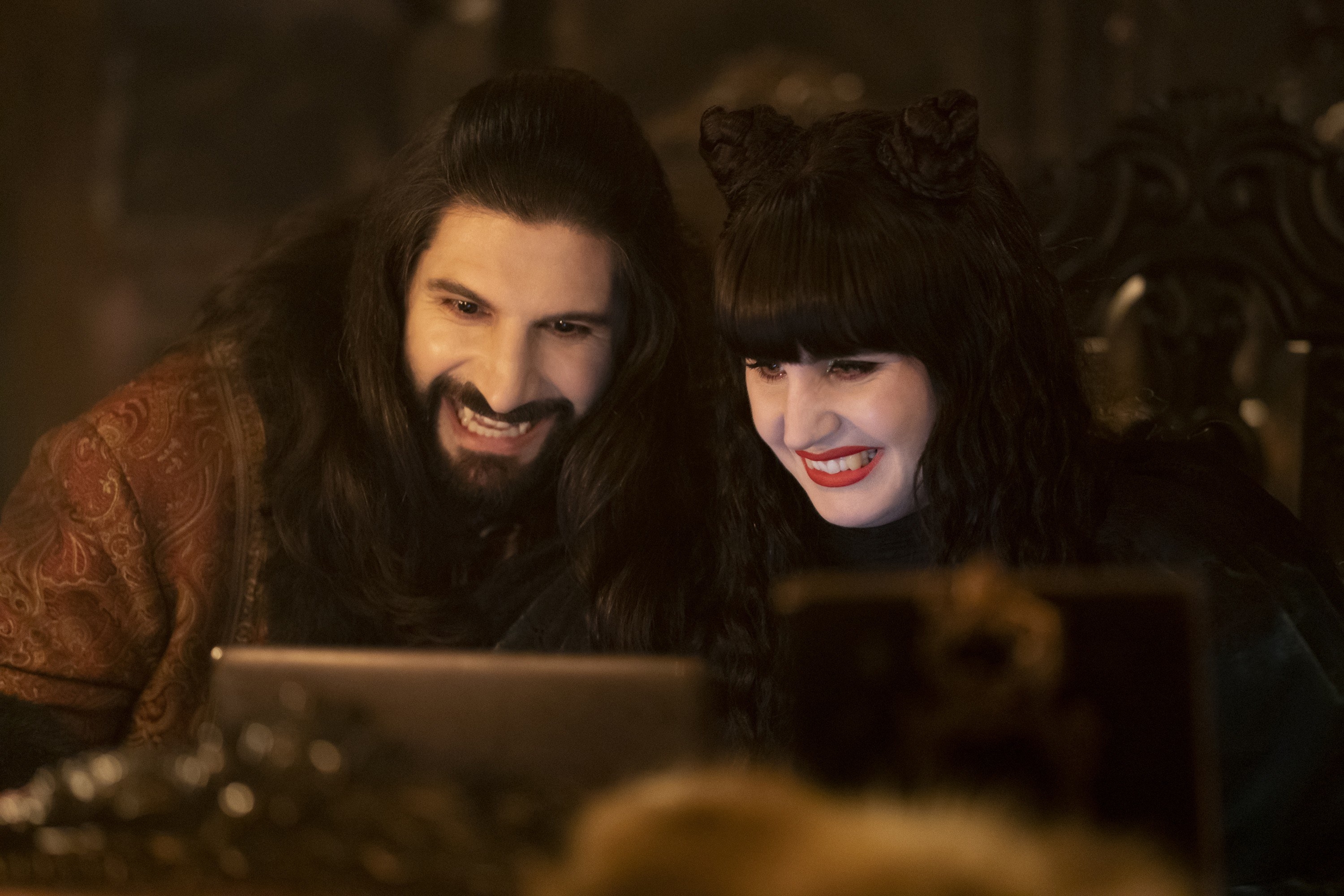 Kayvan Novak and Natasia Demetriou look at a laptop
