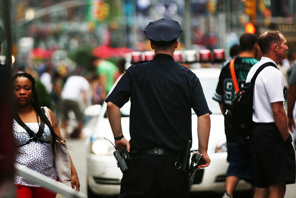 A New York cop has his hand on his gun in a crowded intersection