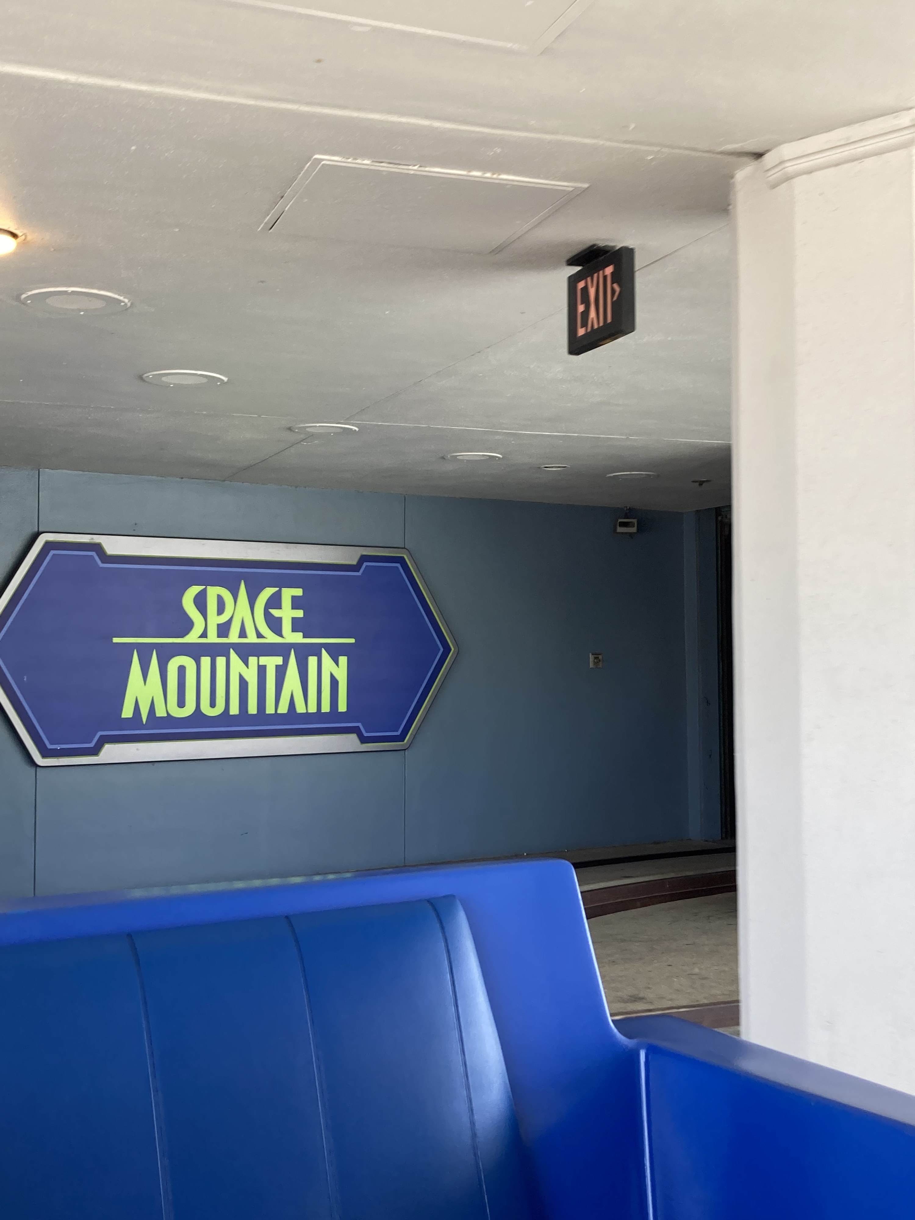 a rollercoaster seat and the space mountain sign on the wall behind it
