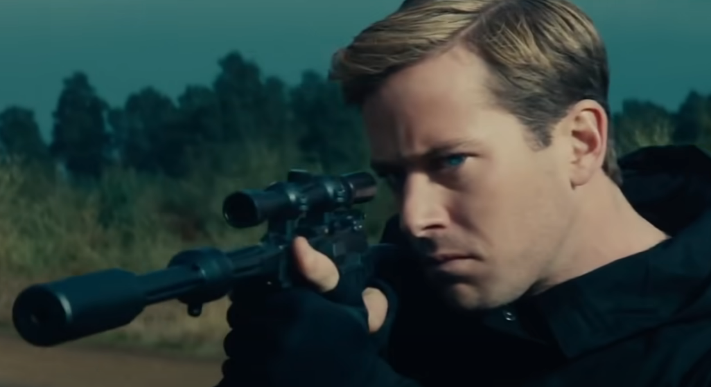 Armie Hammer as Illya holding up a weapon