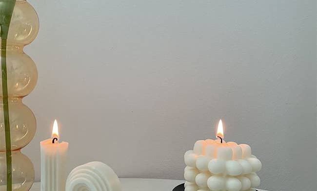 two wax candles, one looks like a bubble cube and another is curved and layered