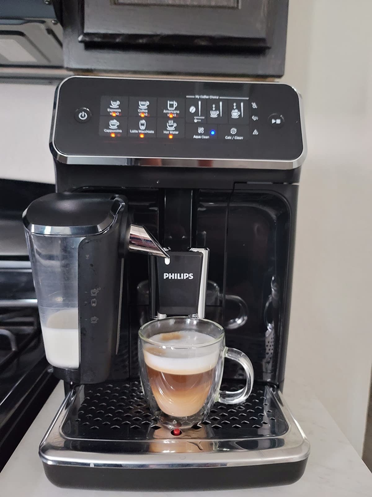 reviewer image of the espresso machine and a mug full of coffee topped with milk foam