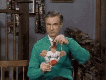 Mr. Rogers putting on a clown mask