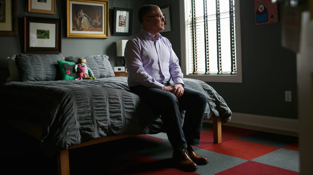 Jim Obergefell sits on a bed alone, looking out a window