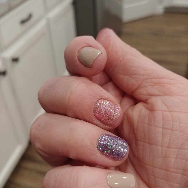 reviewer wearing sparkly pink, purple, and light beige gel polish from the set