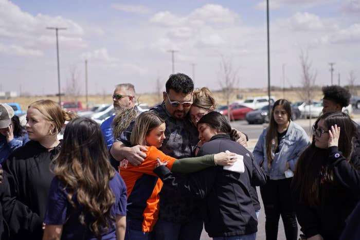 A group of four people hug in a parking lot