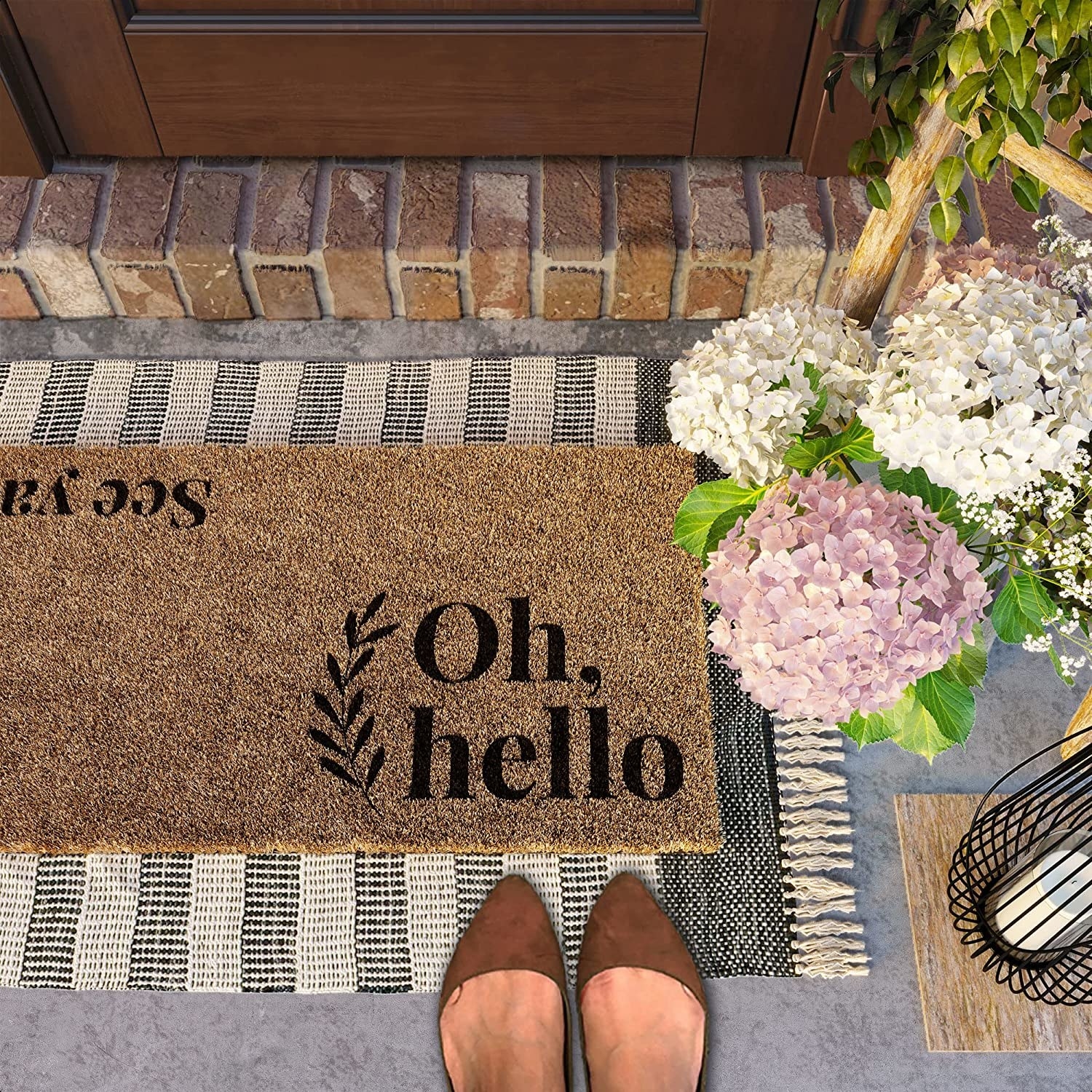 a person standing over the door mat that says oh, hello