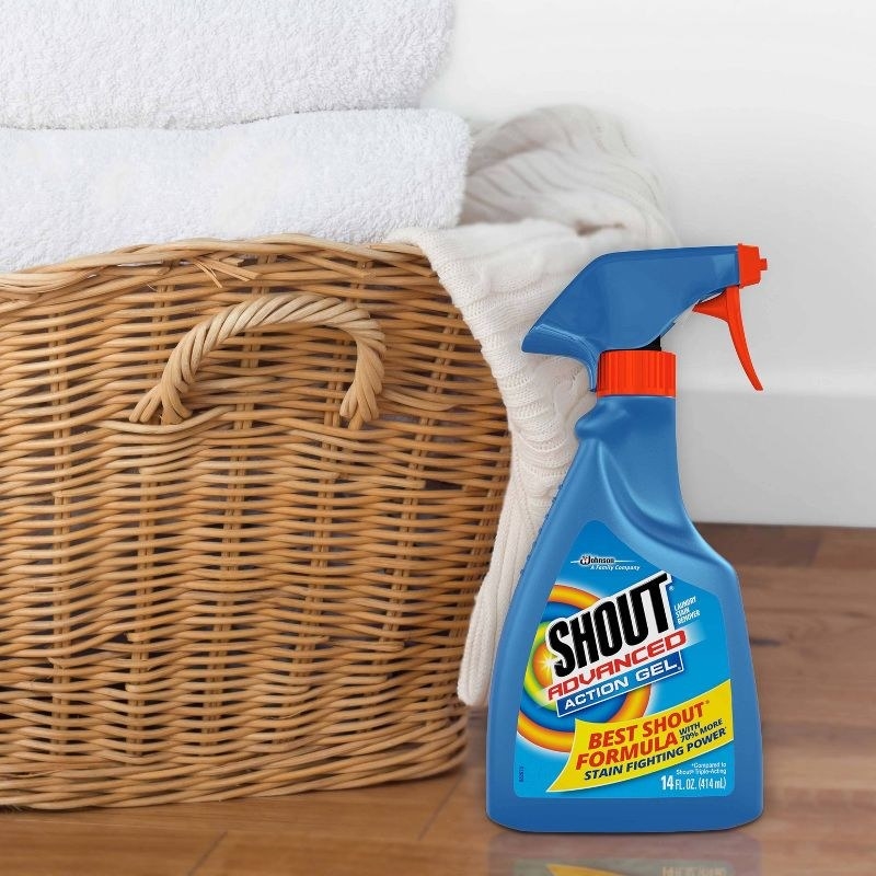 blue spray bottle of shout next to laundry basket