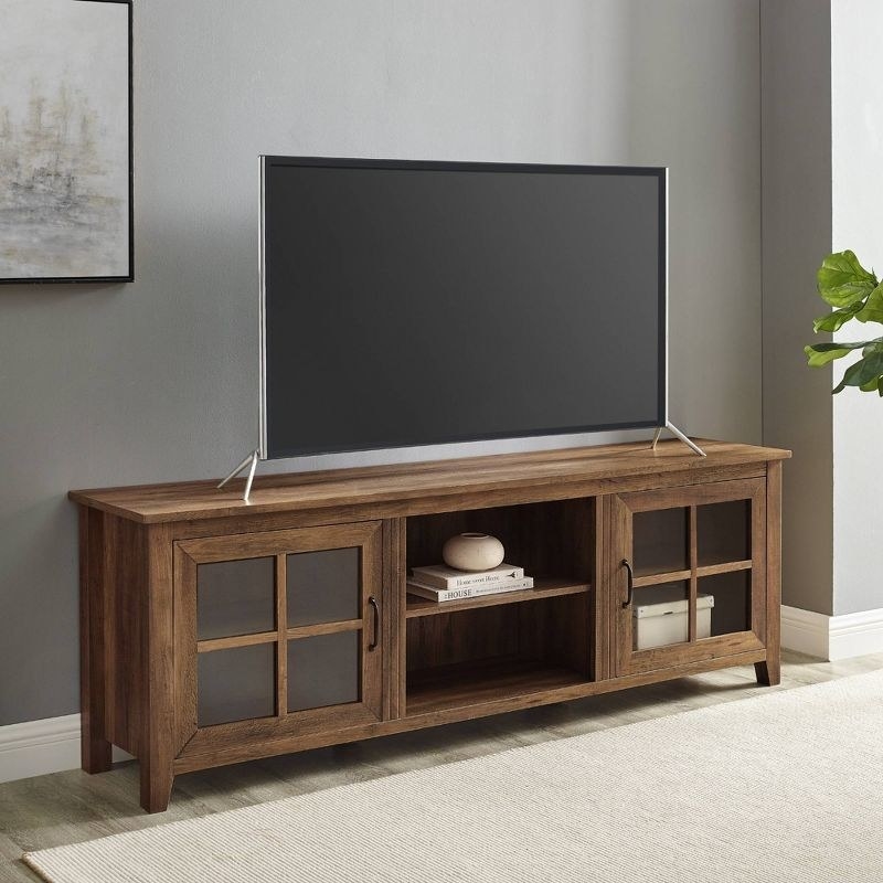 the wood and glass TV stand with a TV on top