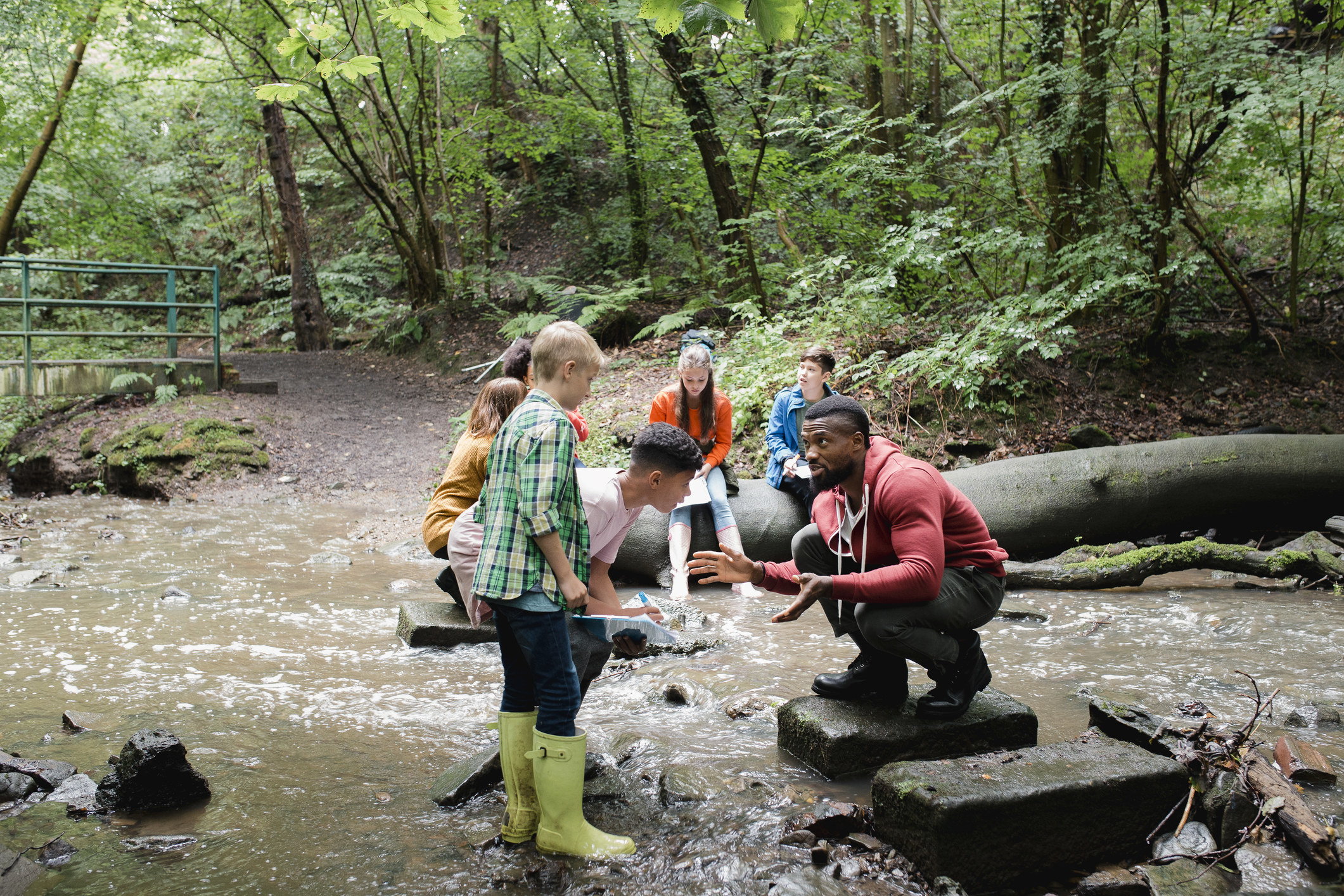 An adult teaches kinds about wildlife in a creek