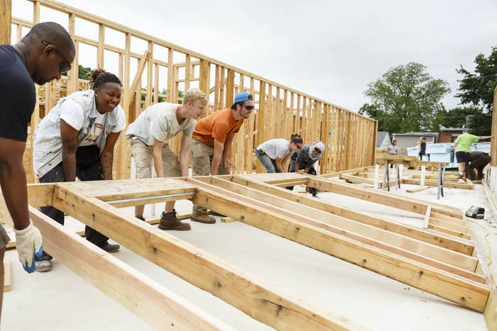 A group of volunteers helps construct the frame of a home