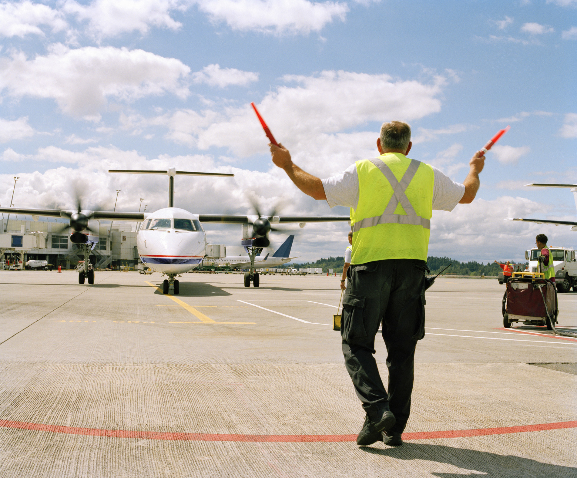 person waving traffic control at a plane