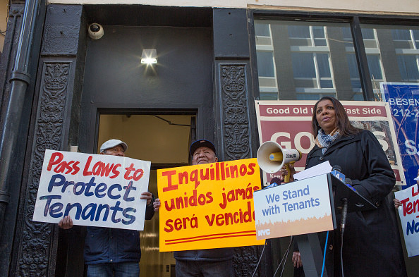 People at a protest with a megaphone and signs supporting tenants&#x27; rights