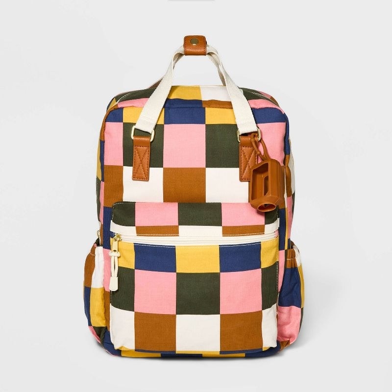 pink, white, navy, yellow, and tan square patterned zippered backpack with a front picket and two size pockets