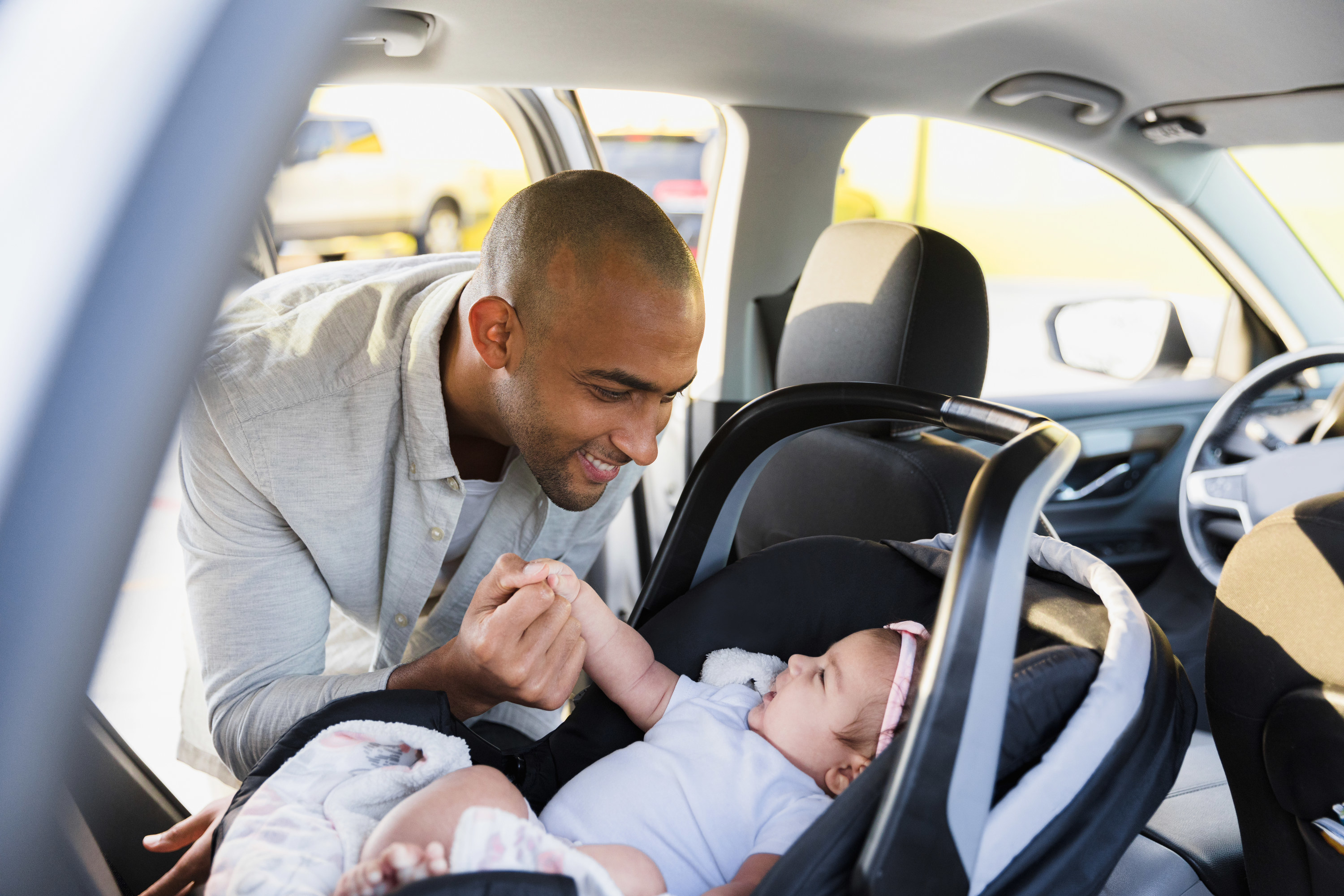 Man looking at baby in a car seat