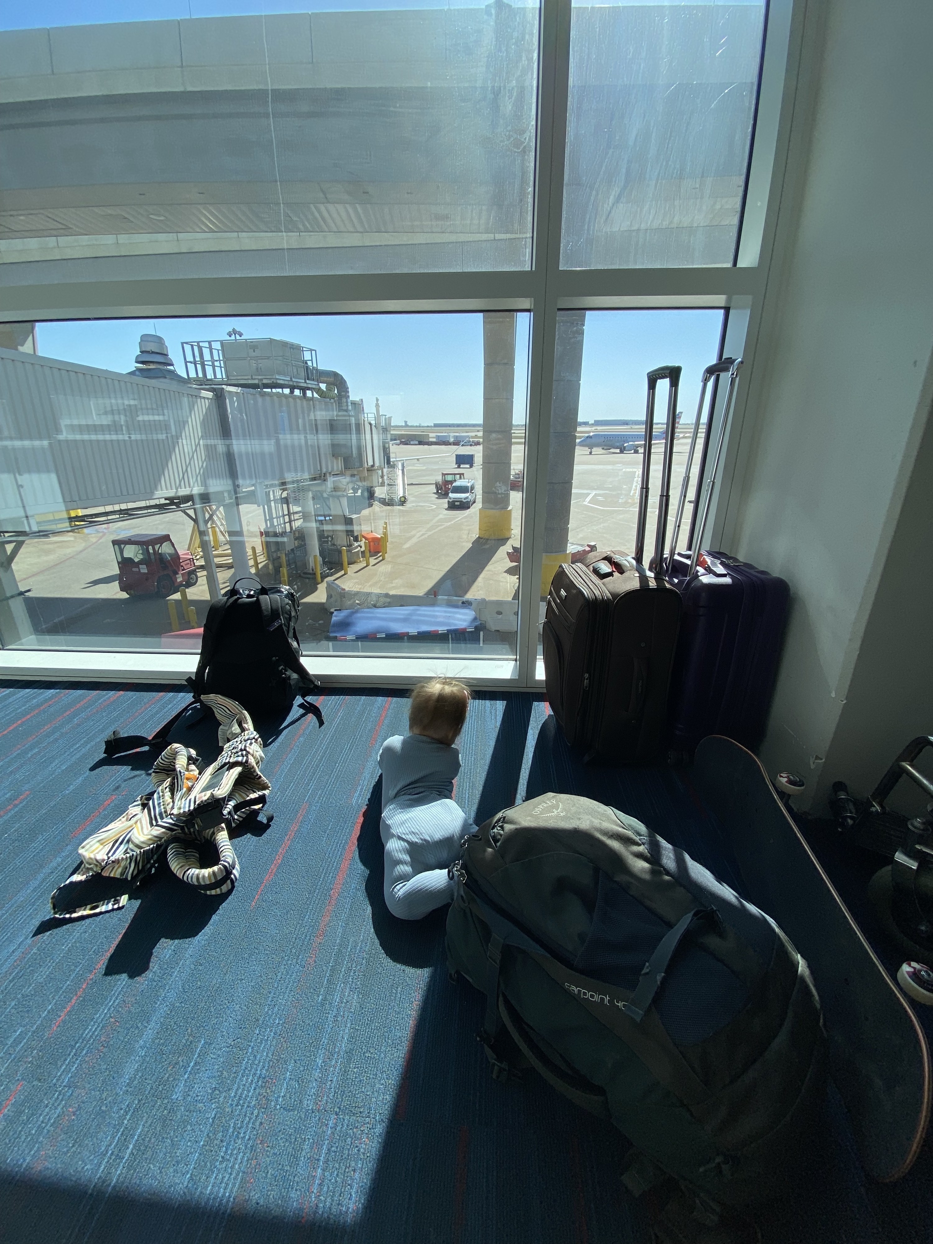 Baby on the floor of an airport with bags