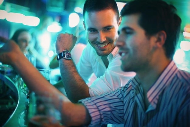 Two men smile while sitting together at a bar
