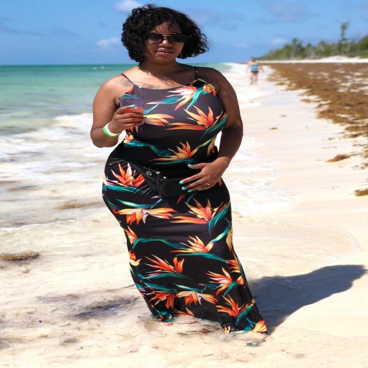 a reviewer wearing the tropical print dress on the beach