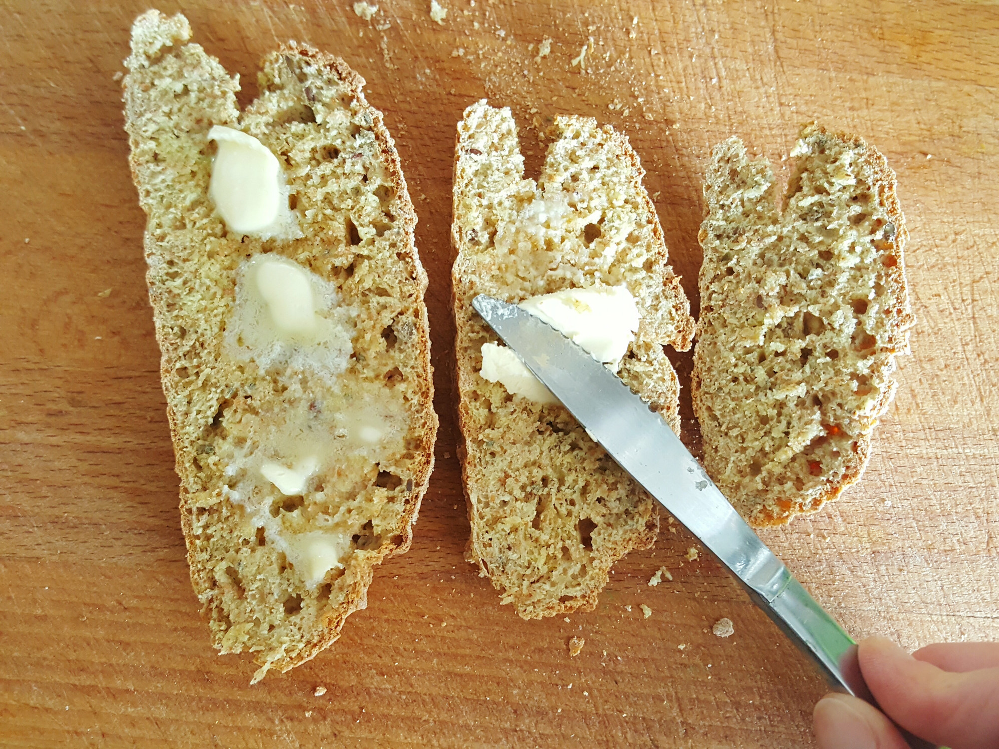 A person spreading butter on bread.