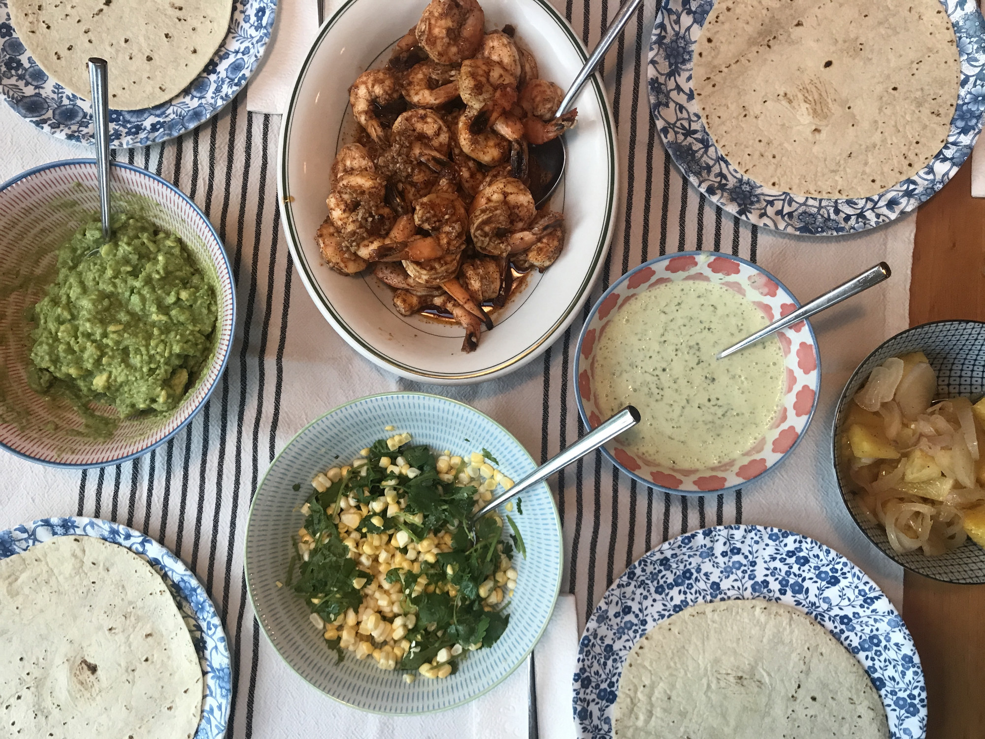 A dinner table topped with shrimp taco ingredients.