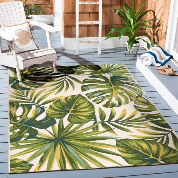 Palm leaf print outdoor rug on a patio with a white Adirondack chair on it