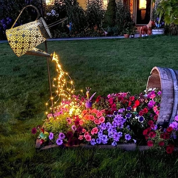 Lit up watering can and string lights that look like they are watering outdoor flowers
