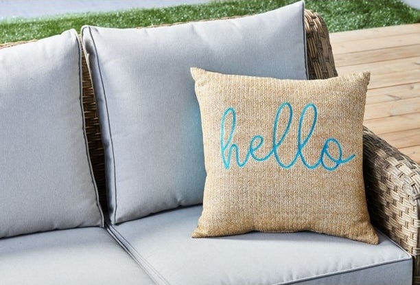 Outdoor pillow with the word hello on it, on an outdoor sofa