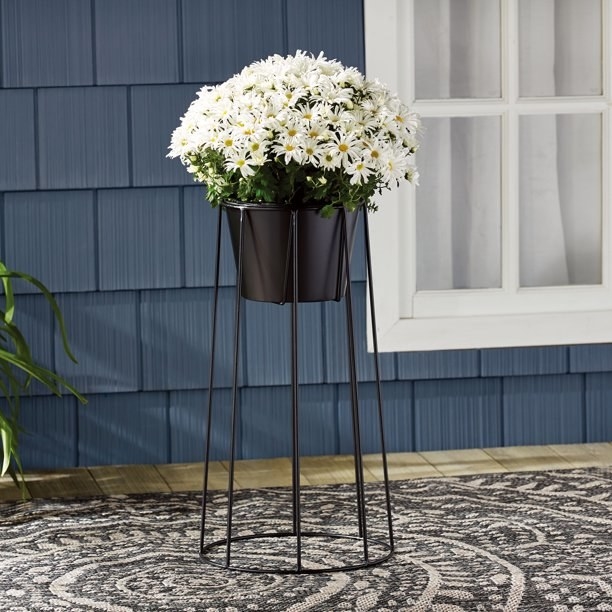 Black plant stand holding pot of flowers